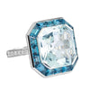 Bague pour femme en or blanc pavée de diamants blancs avec un solitaire d'aigue-marine entouré de topazes bleues. Bague Michaud 143790